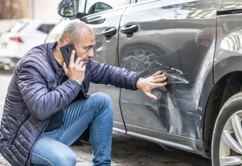 Man inspecting his car after it got hit