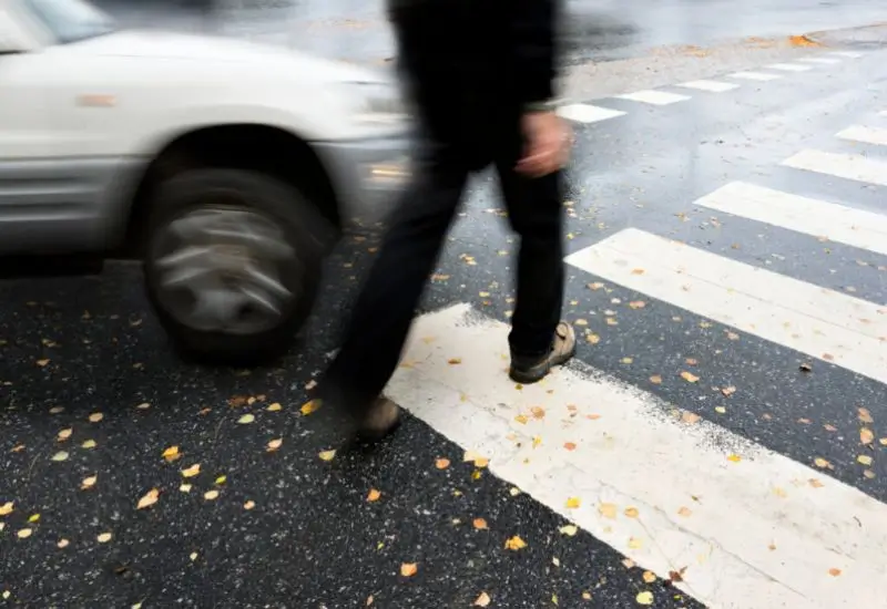 Pedestrian walking on the street as a car is about to turn