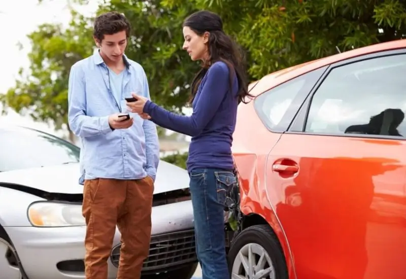 Two individuals exchanging information after car accident