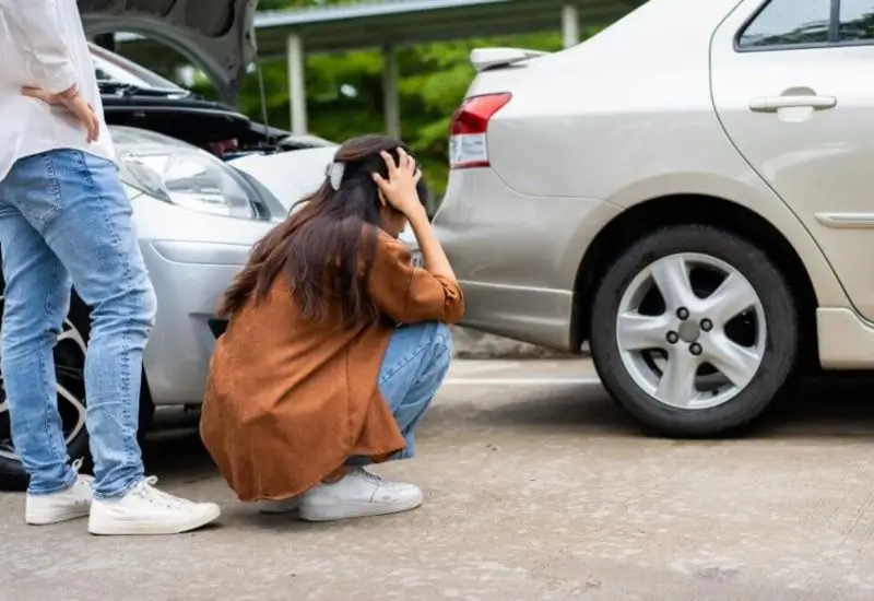 Woman looking at car after car accident