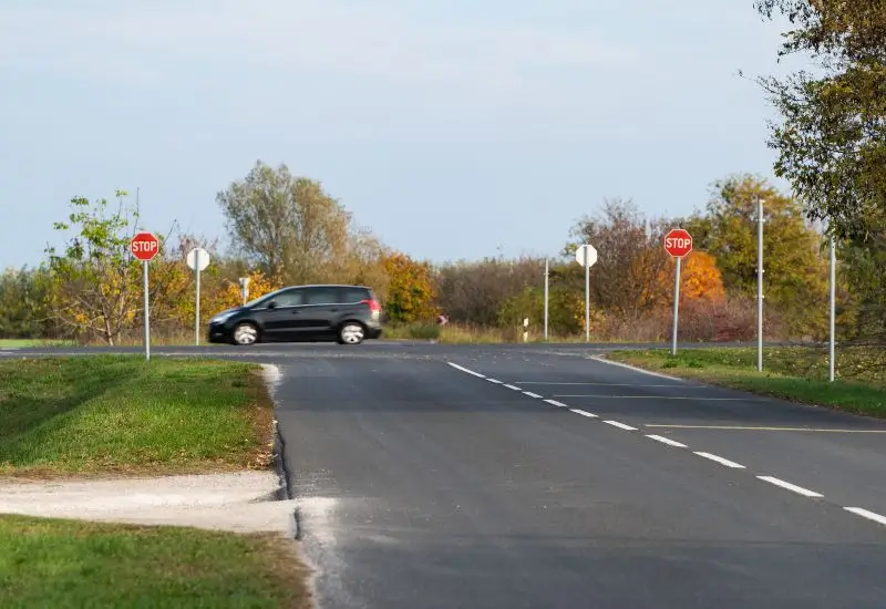 Stop sign at a rural intersection with a passing car 