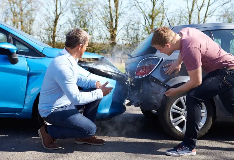 Two Drivers Arguing After Traffic Accident looking at damage