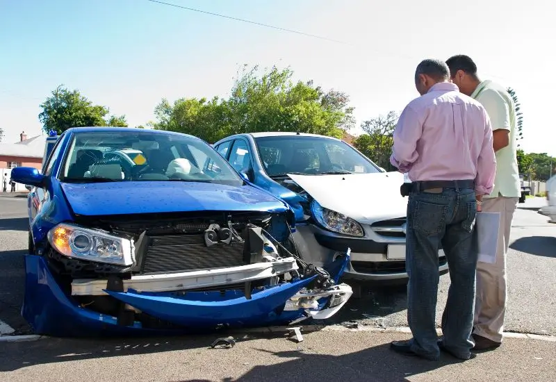 Two men standing next to car accident, discussing the accident