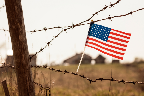 Wire fence and U. S. flag, resembling deportation