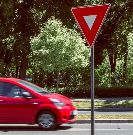 Yield sign near a crossroad with a red car